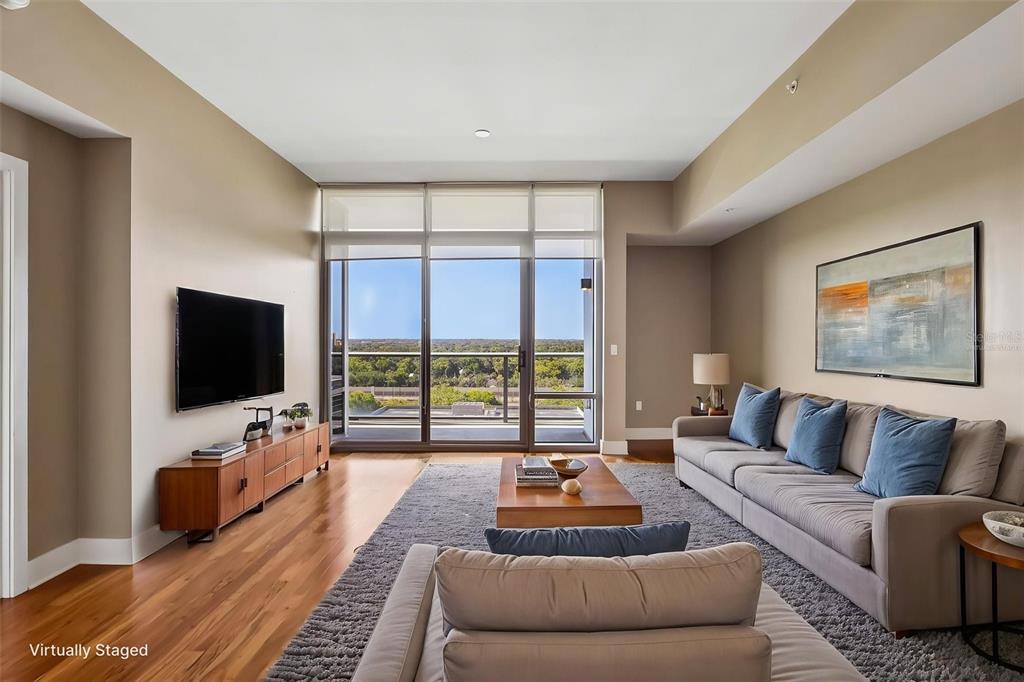 A living room with a large balcony, hardwood floors, and a grey area rug — 260 S OSCEOLA AVENUE UNIT 1005, ORLANDO, FL