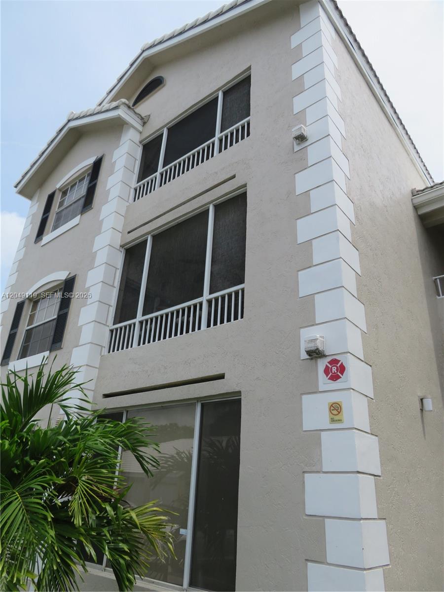 The exterior of a multi-story residential building features stucco walls, screened balconies, and quoined corners — OAKLAND PARK, FL