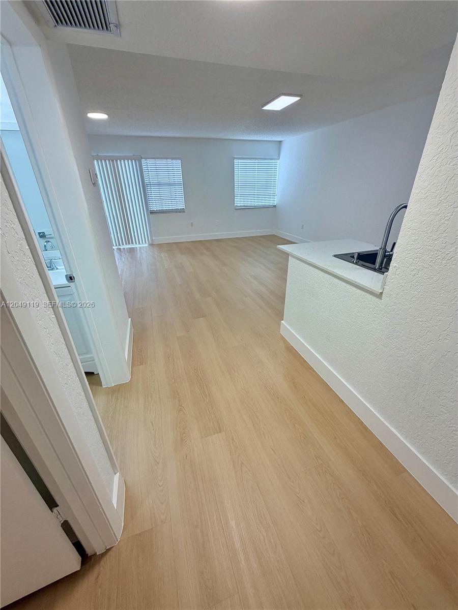 An open-concept living area features light wood-look flooring and a kitchen pass-through counter — OAKLAND PARK, FL