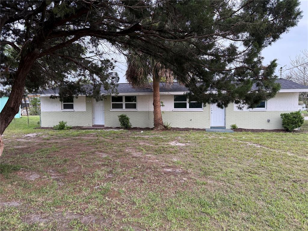 A single-story duplex with a light green brick exterior and two white front doors — 7228 NEW YORK AVENUE, HUDSON, FL