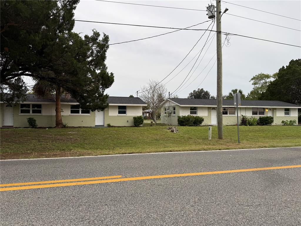 Two single-story residential buildings with light green siding sit behind a paved road — 7228 NEW YORK AVENUE, HUDSON, FL