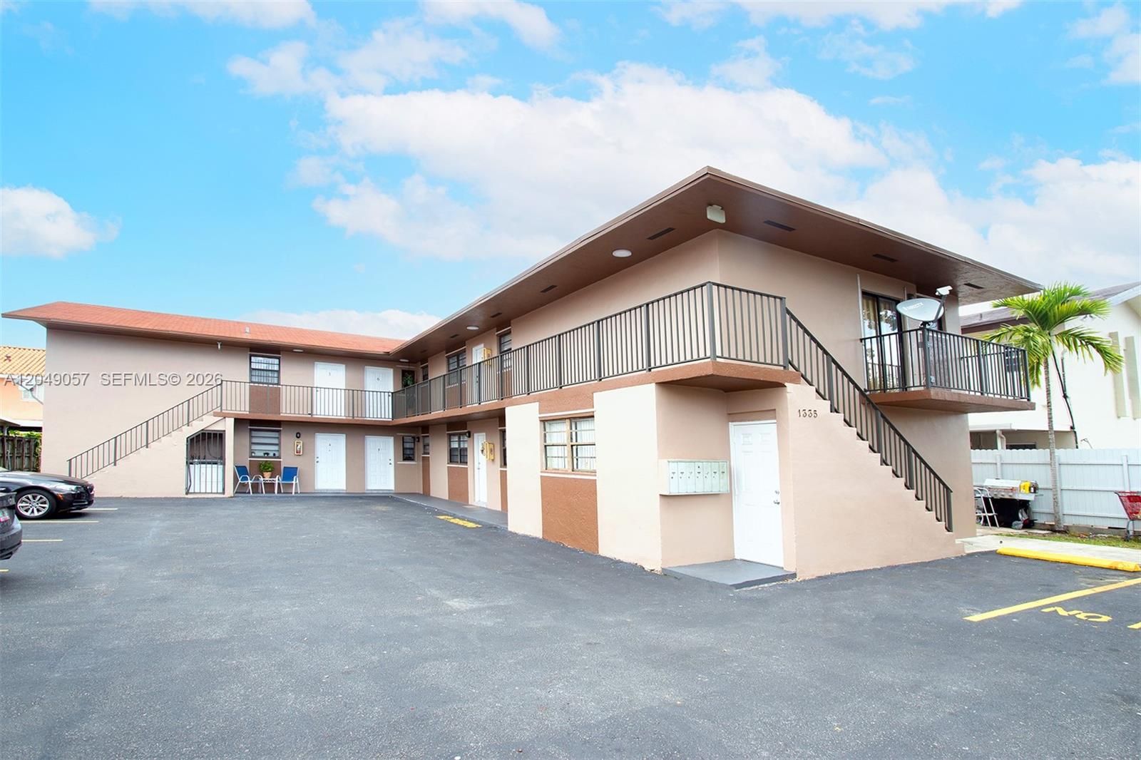 A two-story apartment building with a parking lot and exterior staircases — HIALEAH, FL