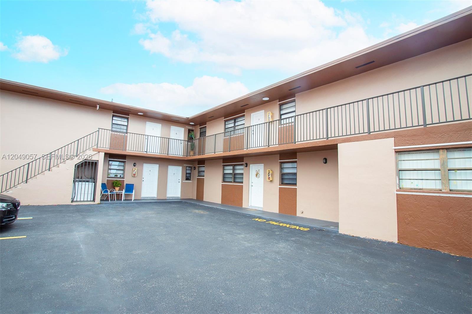 An exterior view of a two-story apartment building with a parking lot in front — HIALEAH, FL