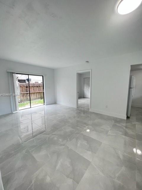 An empty room with white walls, light gray tile flooring, and a sliding glass door — HIALEAH, FL