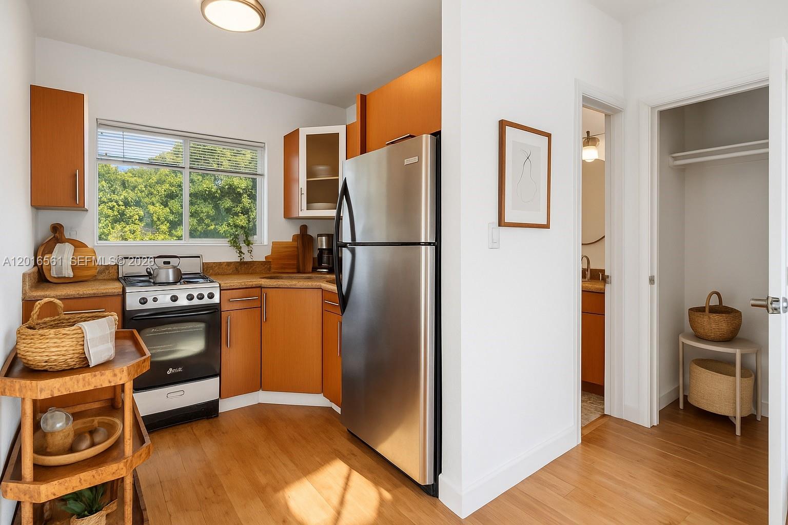 A kitchen features wood cabinets, stainless steel appliances, and a doorway leading to a closet — 1010 Pennsylvania Ave # 14, Miami Beach FL 33139, MIAMI BEACH, FL
