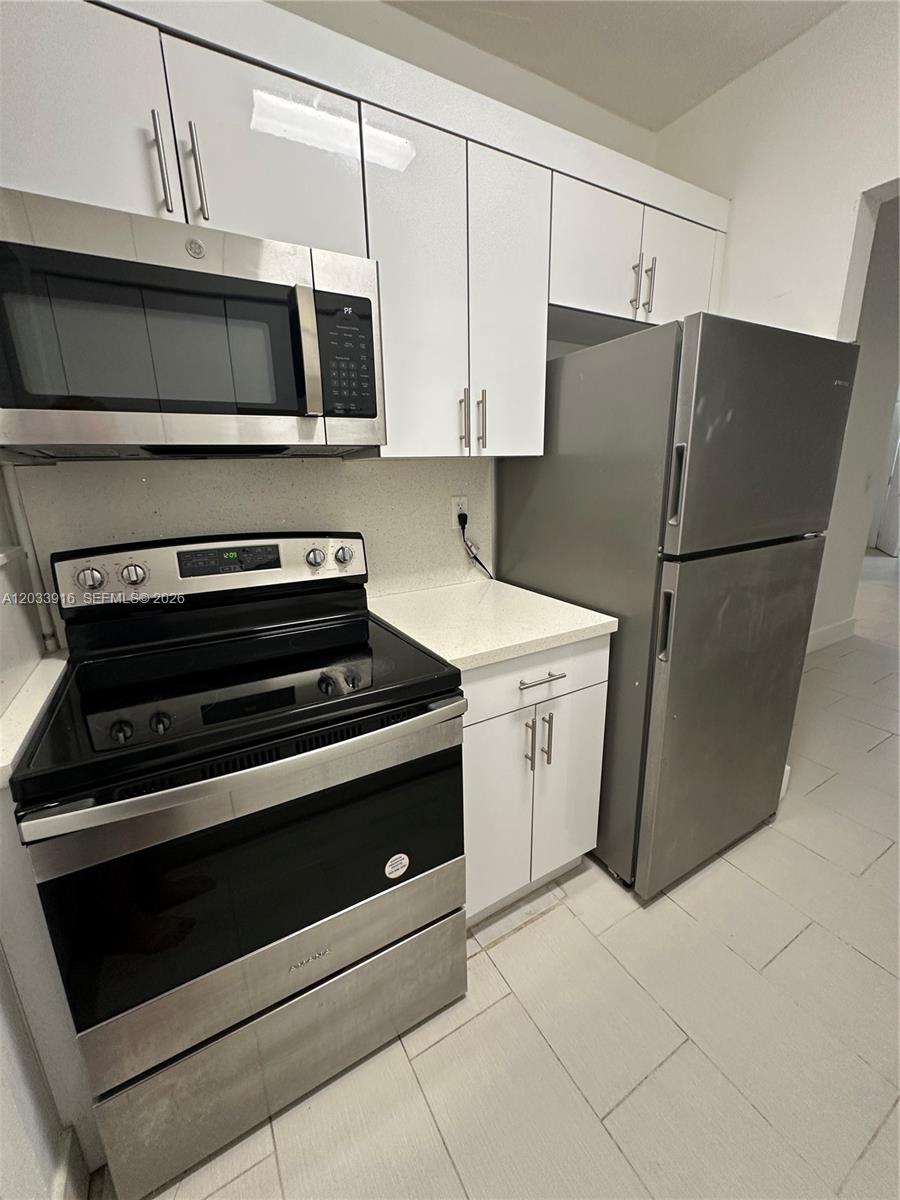 A kitchen features white cabinets, stainless steel appliances, and light-colored countertops — 8205 Crespi Blvd # 3, Miami Beach FL 33141, MIAMI BEACH, FL