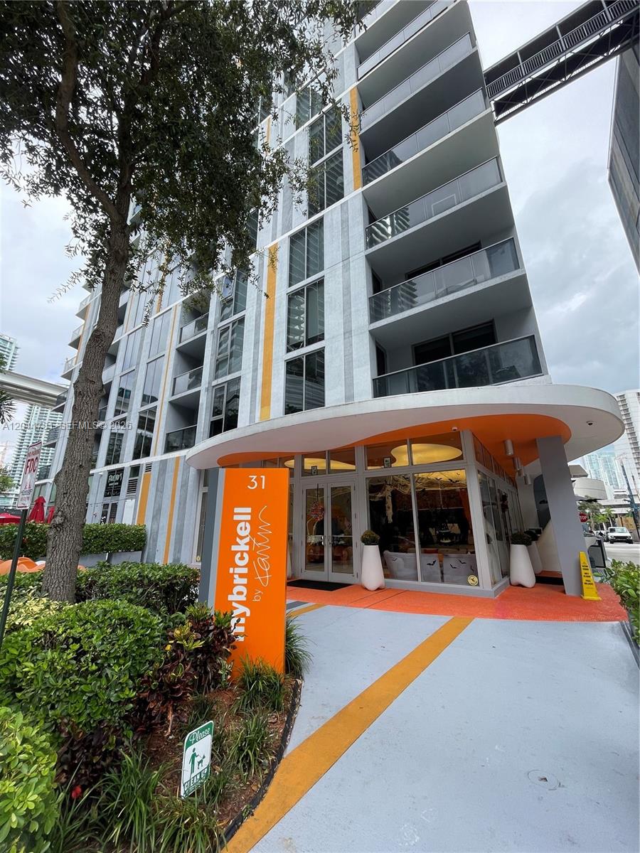 The exterior of a modern apartment building features an orange entrance sign and walkway — 31 SE 6th St # 2503, Miami FL 33131, MIAMI, FL