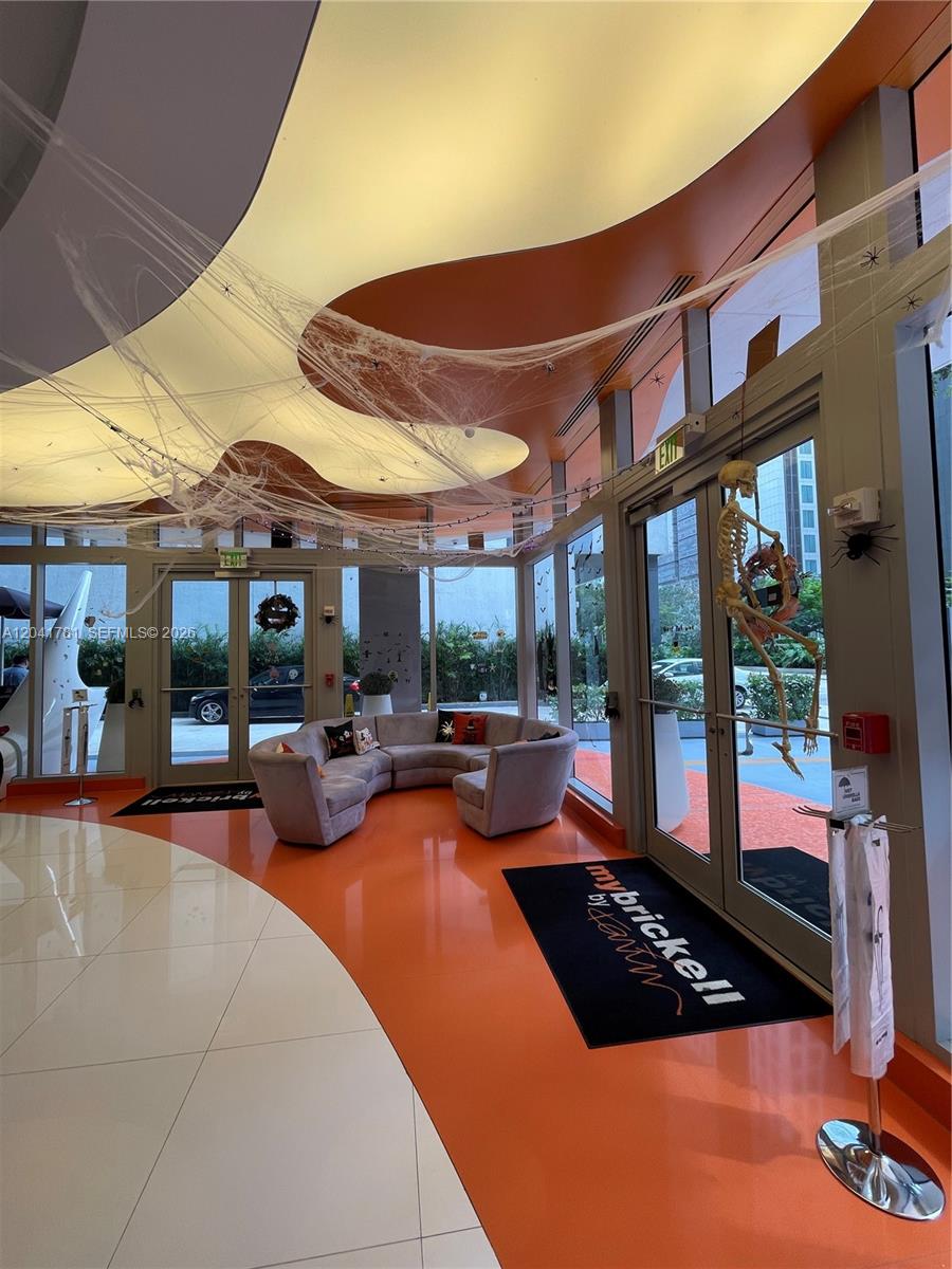 A lobby area features orange flooring, a curved sofa, and Halloween decorations hanging from the ceiling — 31 SE 6th St # 2503, Miami FL 33131, MIAMI, FL
