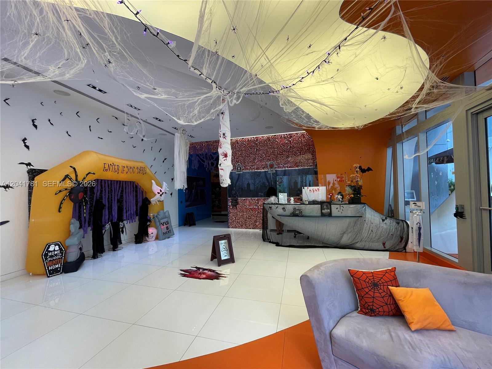 A modern lobby is decorated for Halloween with an inflatable archway, cobwebs, and themed decor — 31 SE 6th St # 2503, Miami FL 33131, MIAMI, FL