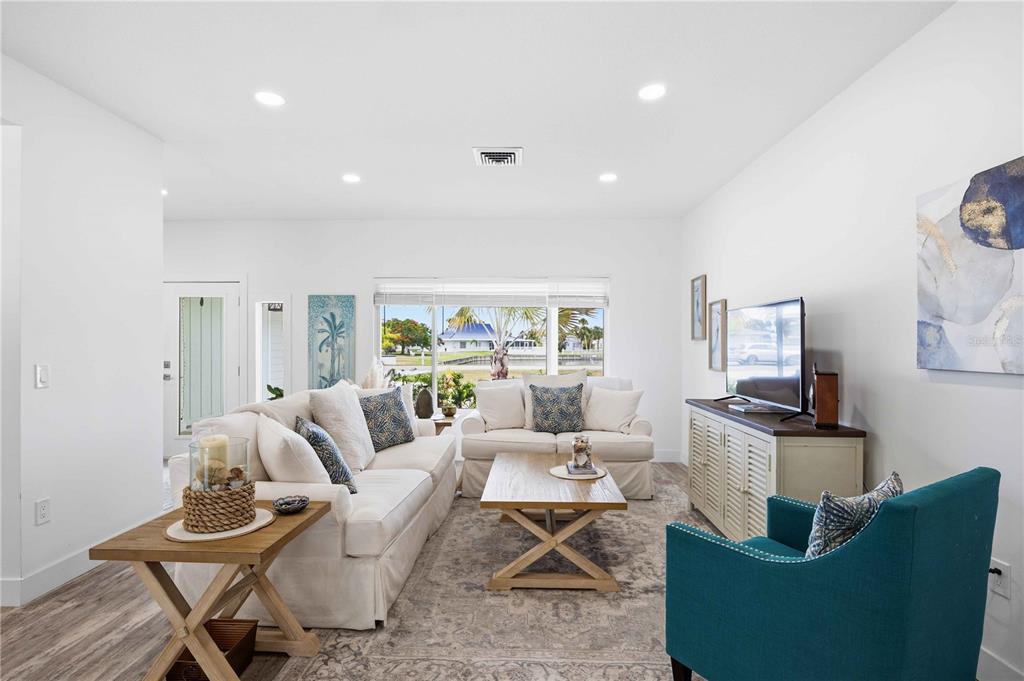 A bright living room features white sofas, a wooden coffee table, and a teal armchair — 1707 BELVIDERE ROAD, ENGLEWOOD, FL