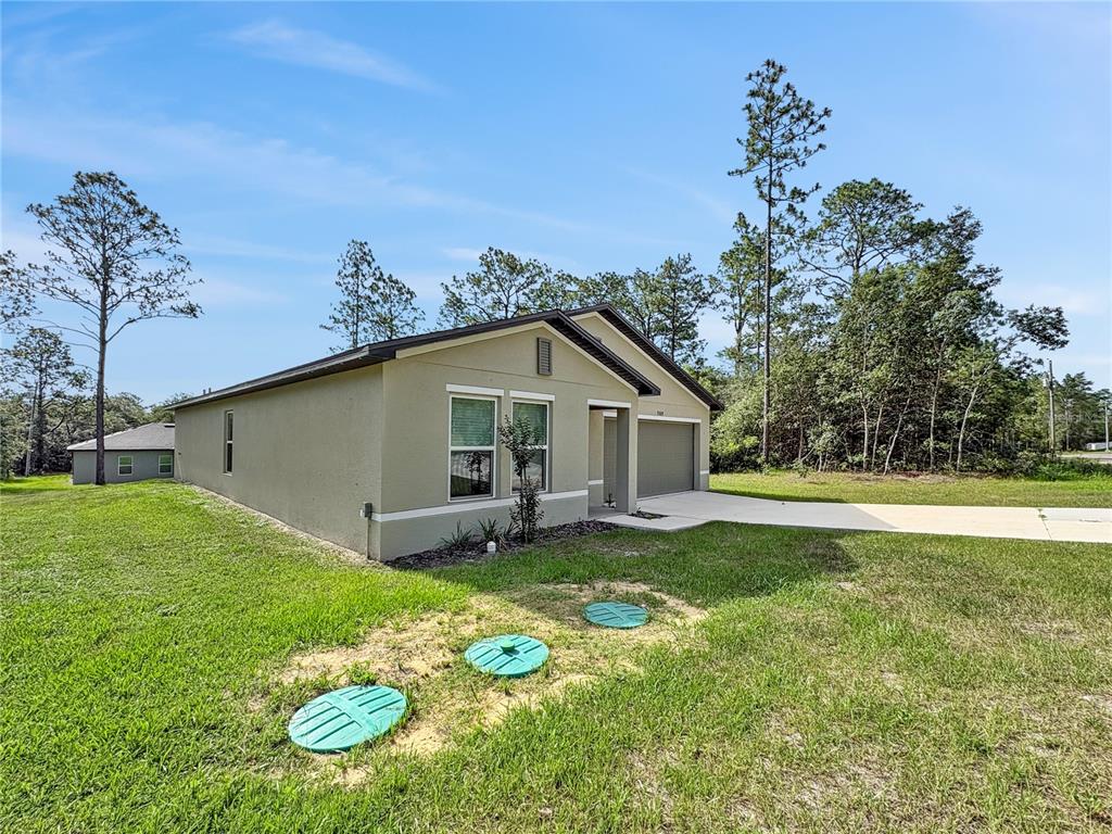 A single-story house with a tan exterior and three green septic tank covers in the yard — 7109 N REGENT TERRACE, CITRUS SPRINGS, FL