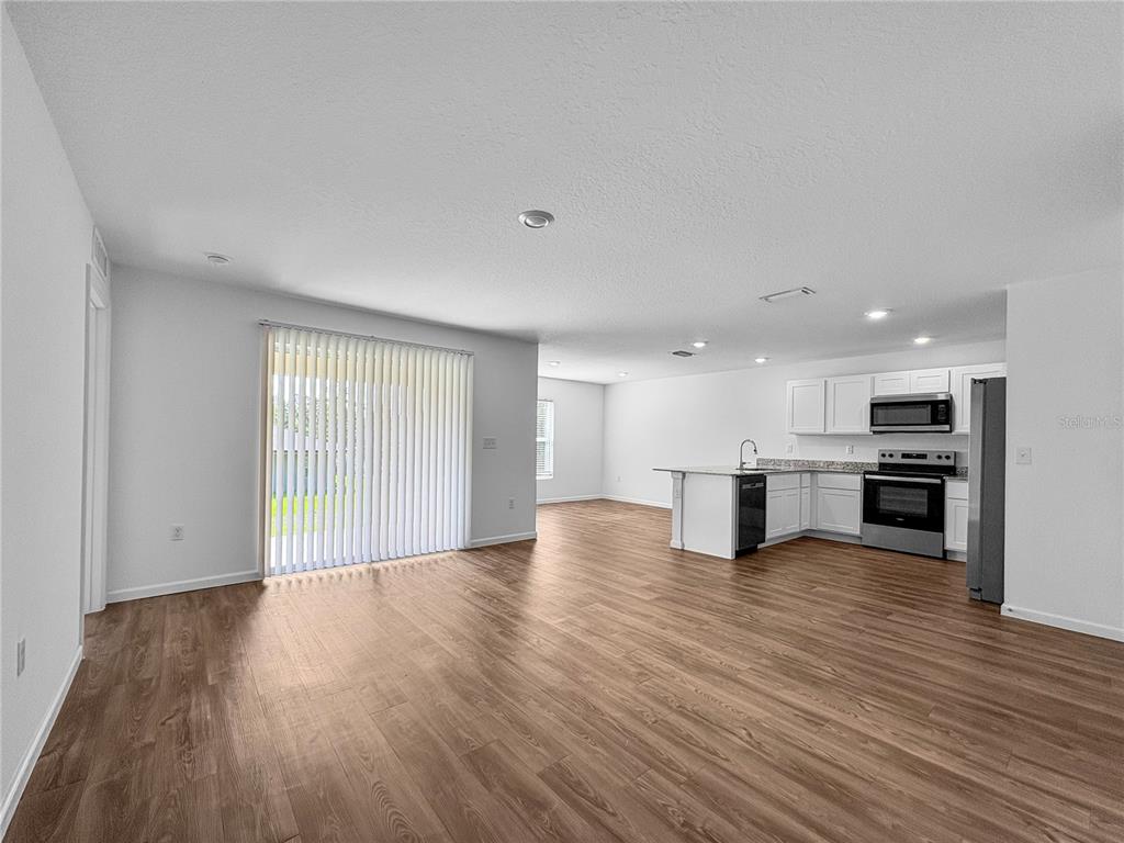 An open-concept kitchen and living area features wood-look flooring and white cabinetry — 7109 N REGENT TERRACE, CITRUS SPRINGS, FL