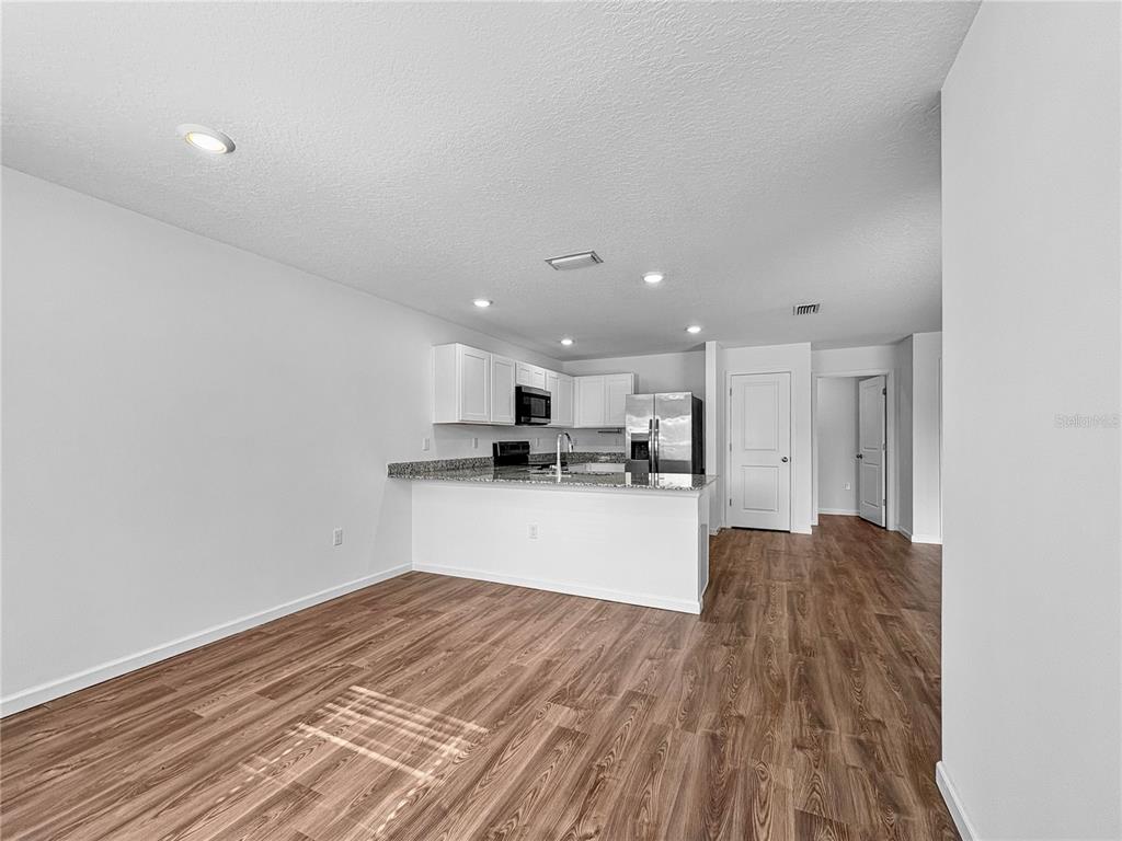 An open-concept kitchen with white cabinets, granite countertops, and wood-look flooring — 7109 N REGENT TERRACE, CITRUS SPRINGS, FL