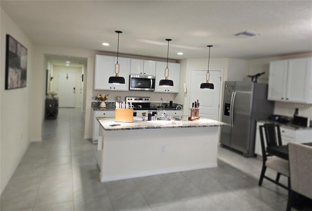 A kitchen features white cabinets, granite countertops, a central island, and three pendant lights — 16706 SUNBURST LAKE STREET, WIMAUMA, FL