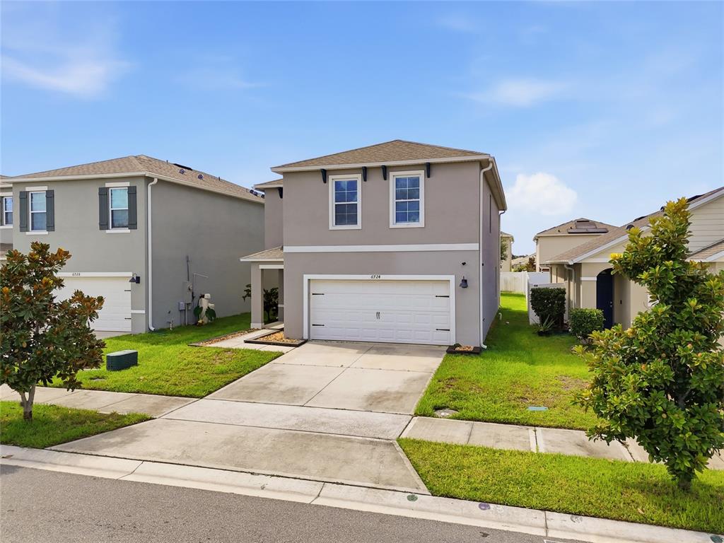 A two-story suburban house with a gray stucco exterior and a two-car garage — 6724 HUNTLEIGH HAMMOCK ROAD, HARMONY, FL