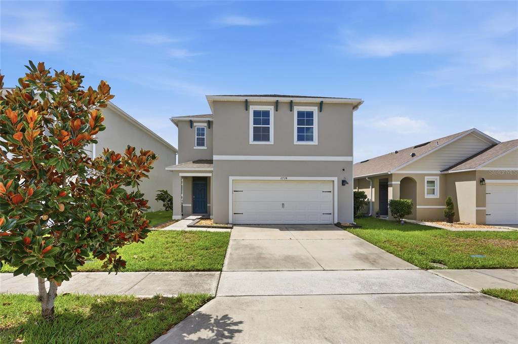 A two-story house with a beige exterior, a two-car garage, and a concrete driveway — 6724 HUNTLEIGH HAMMOCK ROAD, HARMONY, FL