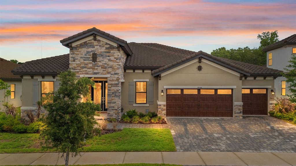 A single-story house with a stone facade, tile roof, and a three-car garage — 14544 SWISS BRIDGE DRIVE, LITHIA, FL