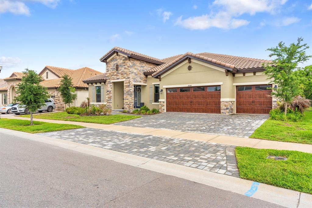 A single-story house with a stone facade, tile roof, and a paved driveway — 14544 SWISS BRIDGE DRIVE, LITHIA, FL