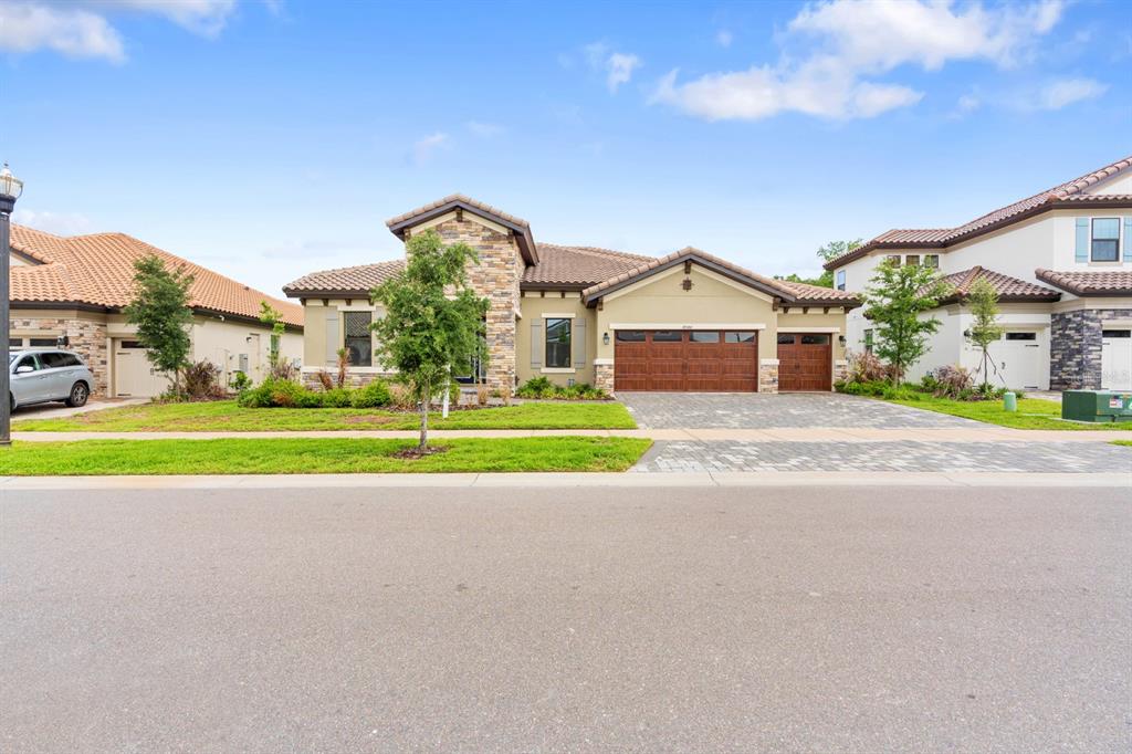 A single-story house with a stone facade, tile roof, and a three-car garage — 14544 SWISS BRIDGE DRIVE, LITHIA, FL