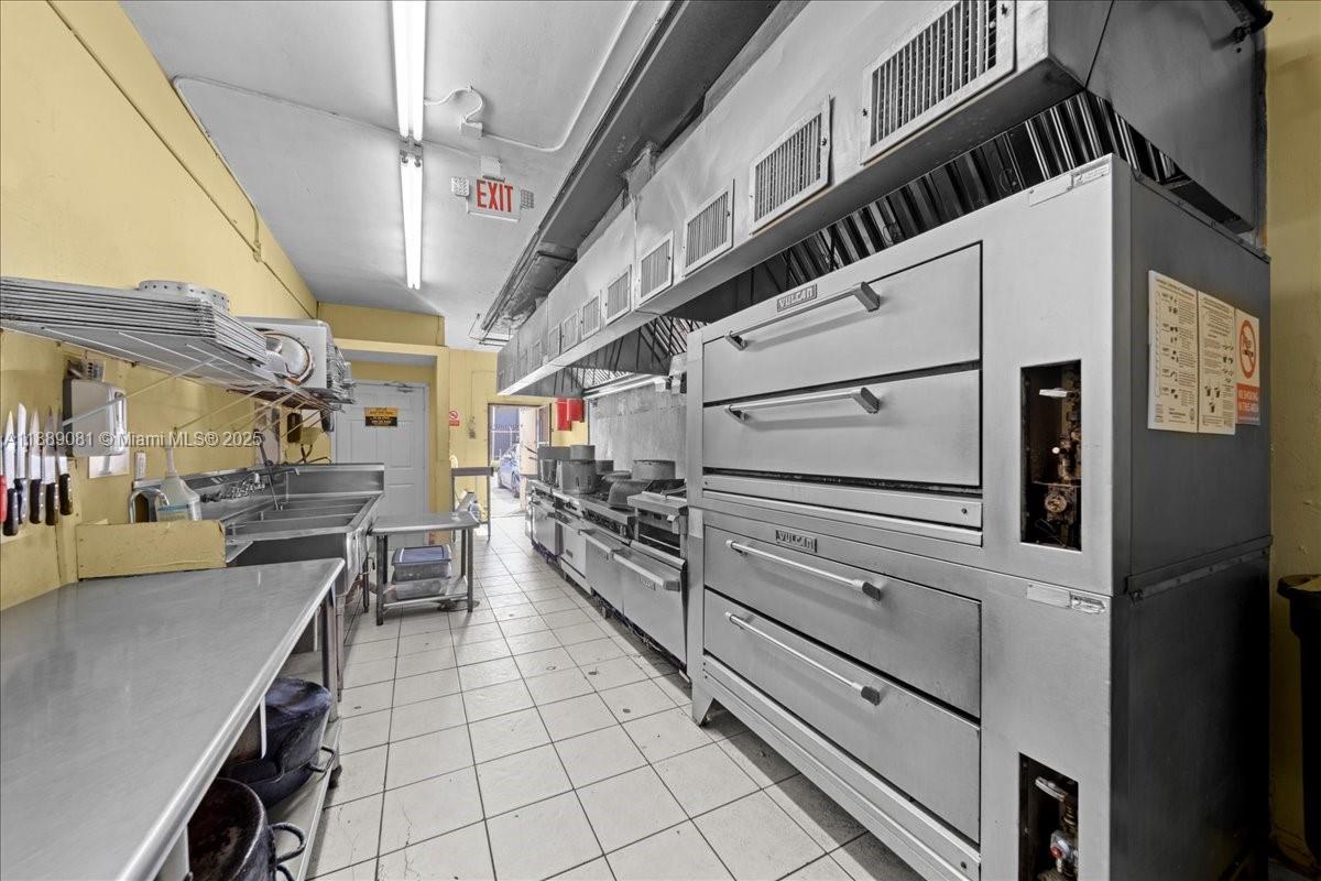 A commercial kitchen features a large stainless steel oven, stainless steel sinks, and tiled floors — 2313 NW 27th Ave, Miami FL 33142, MIAMI, FL