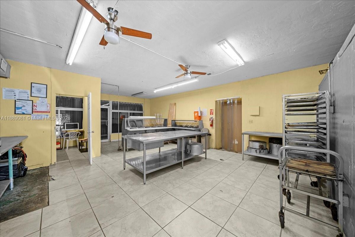 A commercial kitchen space features stainless steel prep tables, a rolling rack, and tile flooring — 2313 NW 27th Ave, Miami FL 33142, MIAMI, FL