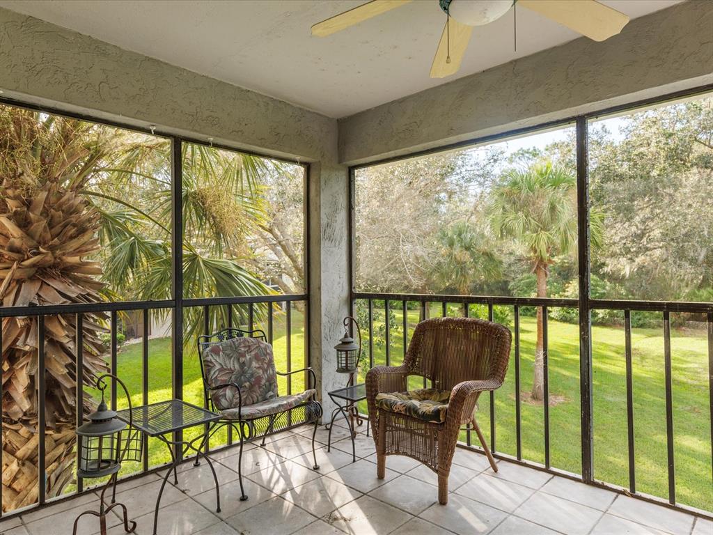 A screened-in porch features tiled flooring, a ceiling fan, and two chairs overlooking a yard — 7794 EAGLE CREEK DRIVE UNIT 7794, SARASOTA, FL