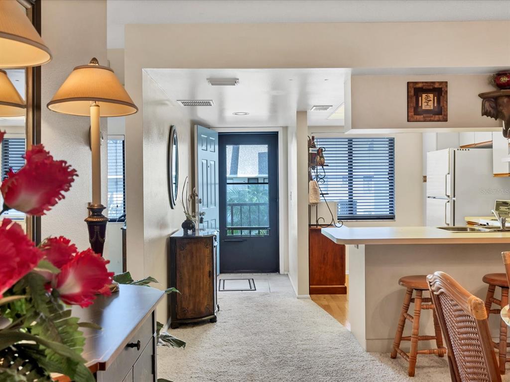 A view from a carpeted dining area looking toward an entryway and a kitchen counter — 7794 EAGLE CREEK DRIVE UNIT 7794, SARASOTA, FL