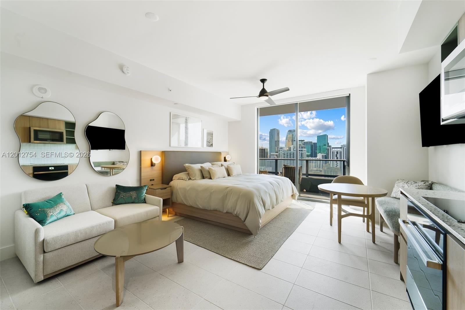 A modern studio apartment features a bed, sofa, dining area, and floor-to-ceiling city view windows — 601 NE 1st Ave # 3210, Miami FL 33132, MIAMI, FL