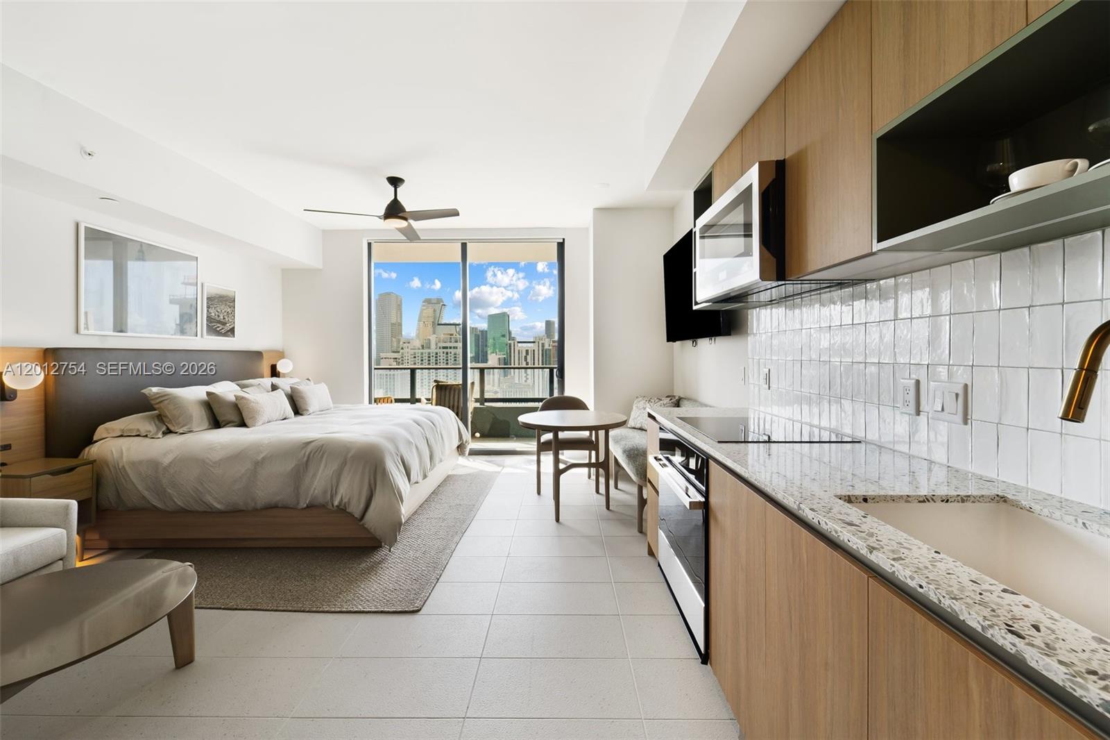 A studio apartment features a bed, kitchenette with light wood cabinets, and a balcony view — 601 NE 1st Ave # 3210, Miami FL 33132, MIAMI, FL