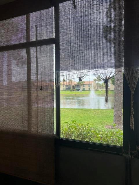 A view of a lake and fountain seen through a window with bamboo shades — 628 Sea Pine Way # H1, FL 33415, FL