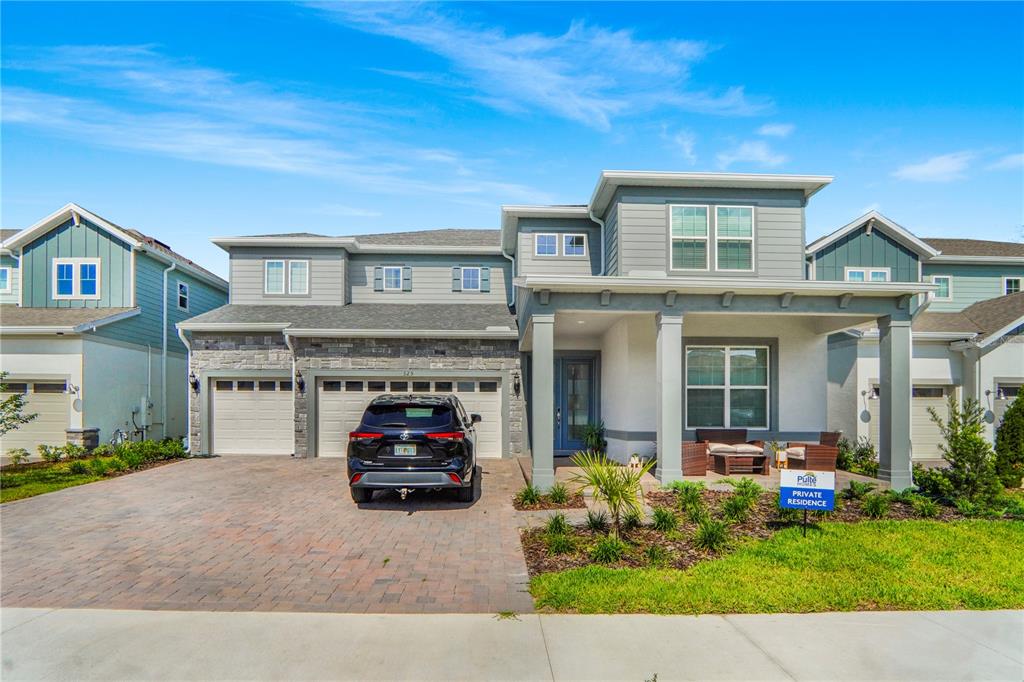 A two-story suburban house with a three-car garage, stone facade, and a covered front porch — 325 CRYSTAL WOOD DRIVE, WINTER GARDEN, FL