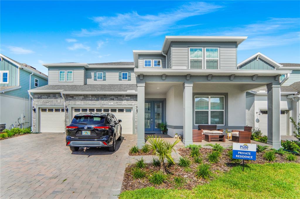 A two-story suburban house with a gray exterior, stone accents, and a paved driveway — 325 CRYSTAL WOOD DRIVE, WINTER GARDEN, FL