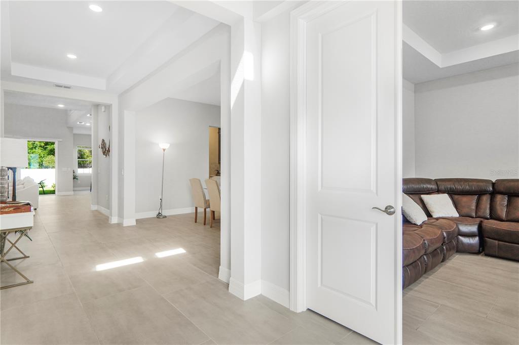 A white door opens into a living room with a brown leather sectional sofa — 325 CRYSTAL WOOD DRIVE, WINTER GARDEN, FL