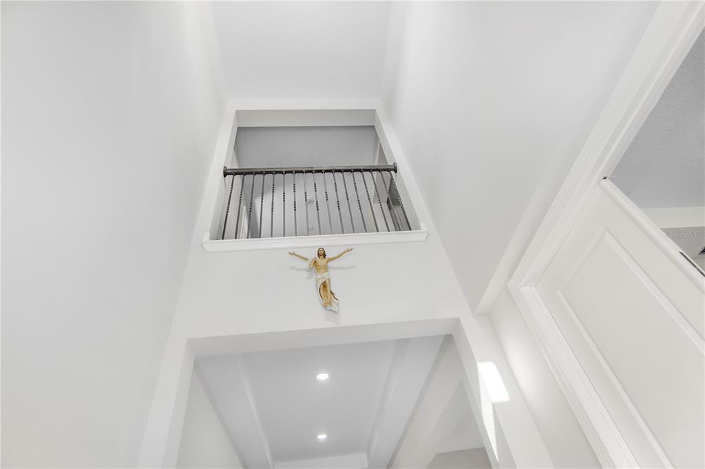 A low-angle view of a two-story foyer featuring a crucifix on a white wall — 325 CRYSTAL WOOD DRIVE, WINTER GARDEN, FL