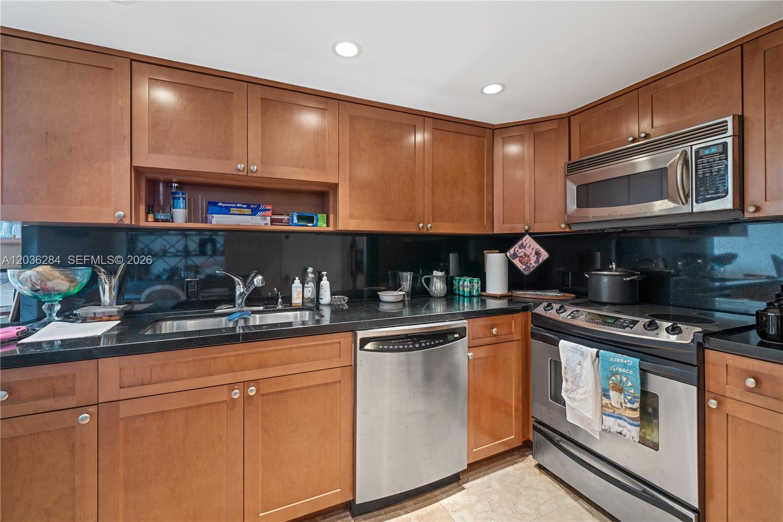 A kitchen features wood cabinets, black countertops, stainless steel appliances, and a black backsplash — 11 Island Ave # 1708, Miami Beach FL 33139, MIAMI BEACH, FL