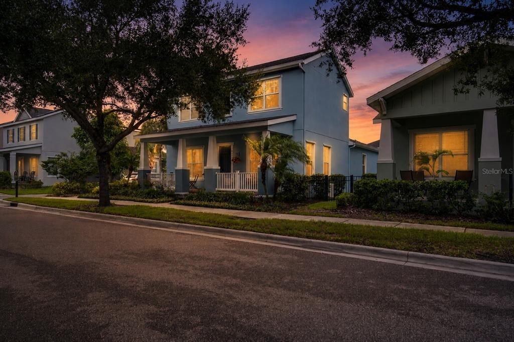 A two-story blue house with a front porch sits along a street at sunset — 6144 CLIFF HOUSE LANE, RIVERVIEW, FL