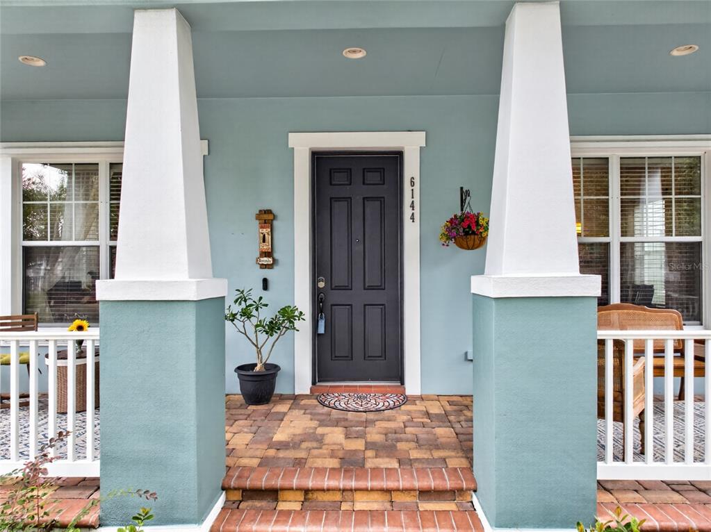 A front porch with a dark door, white columns, and a brick walkway — 6144 CLIFF HOUSE LANE, RIVERVIEW, FL