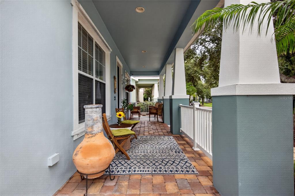 A covered porch features a brick floor, a patterned rug, and seating along the wall — 6144 CLIFF HOUSE LANE, RIVERVIEW, FL