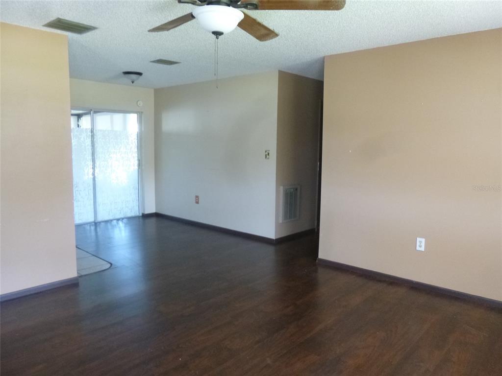 An empty room with dark wood-look flooring, beige walls, and a ceiling fan — 318 CENTRAL AVENUE, FROSTPROOF, FL