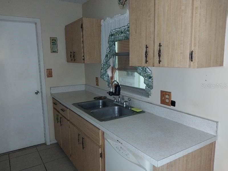 A kitchen features light wood cabinets, a double-basin sink, and a white dishwasher — 318 CENTRAL AVENUE, FROSTPROOF, FL
