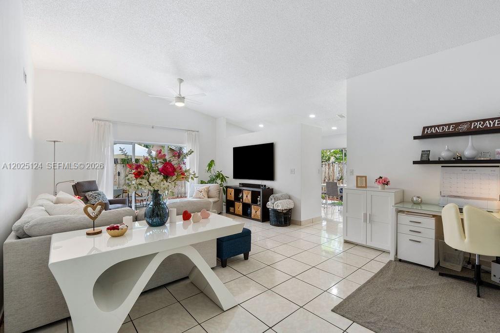 A bright living room features white tile floors, a vaulted ceiling, and an open layout — 19080 NW 77th Ct, Hialeah FL 33015, HIALEAH, FL