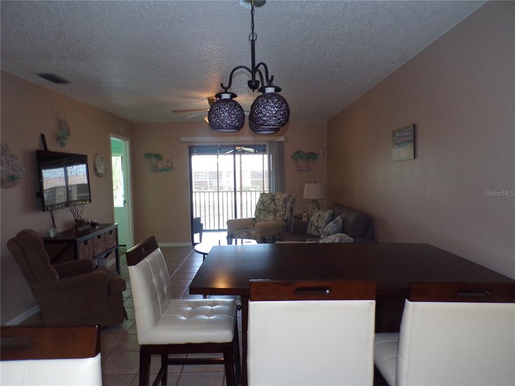 A living and dining area features a dark wood table, white chairs, and a chandelier — 4016 OAKVIEW DRIVE UNIT J8, PUNTA GORDA, FL