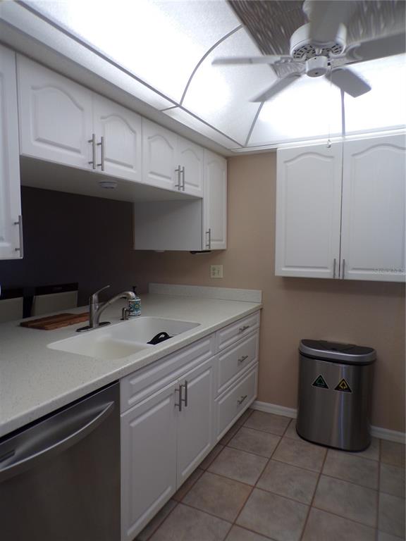 A kitchen features white cabinets, a stainless steel dishwasher, a double sink, and tile flooring — 4016 OAKVIEW DRIVE UNIT J8, PUNTA GORDA, FL