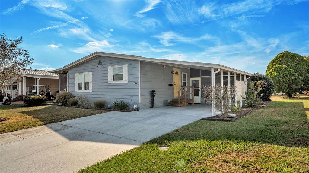 A light blue single-story house with a concrete driveway and a covered front porch — 5079 LODGEWOOD DRIVE, LAKELAND, FL
