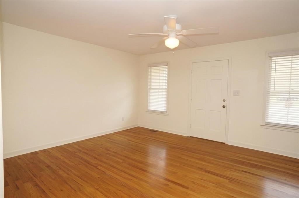 An empty room with hardwood floors, white walls, a ceiling fan, and two windows — 305 S AUDUBON AVENUE, TAMPA, FL