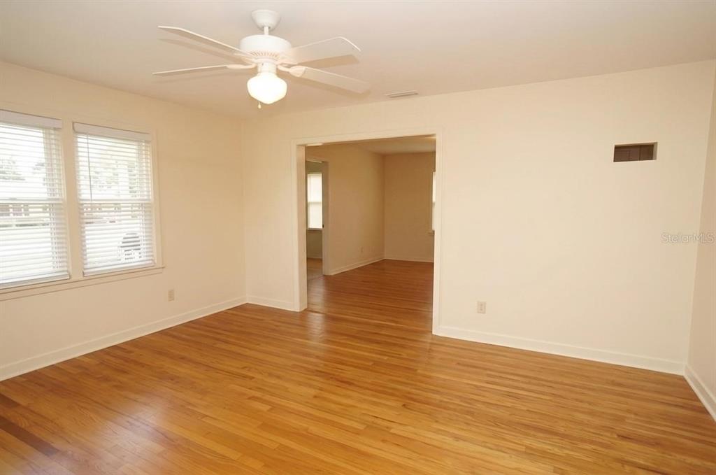 An empty room with hardwood floors, a ceiling fan, and a doorway to another room — 305 S AUDUBON AVENUE, TAMPA, FL