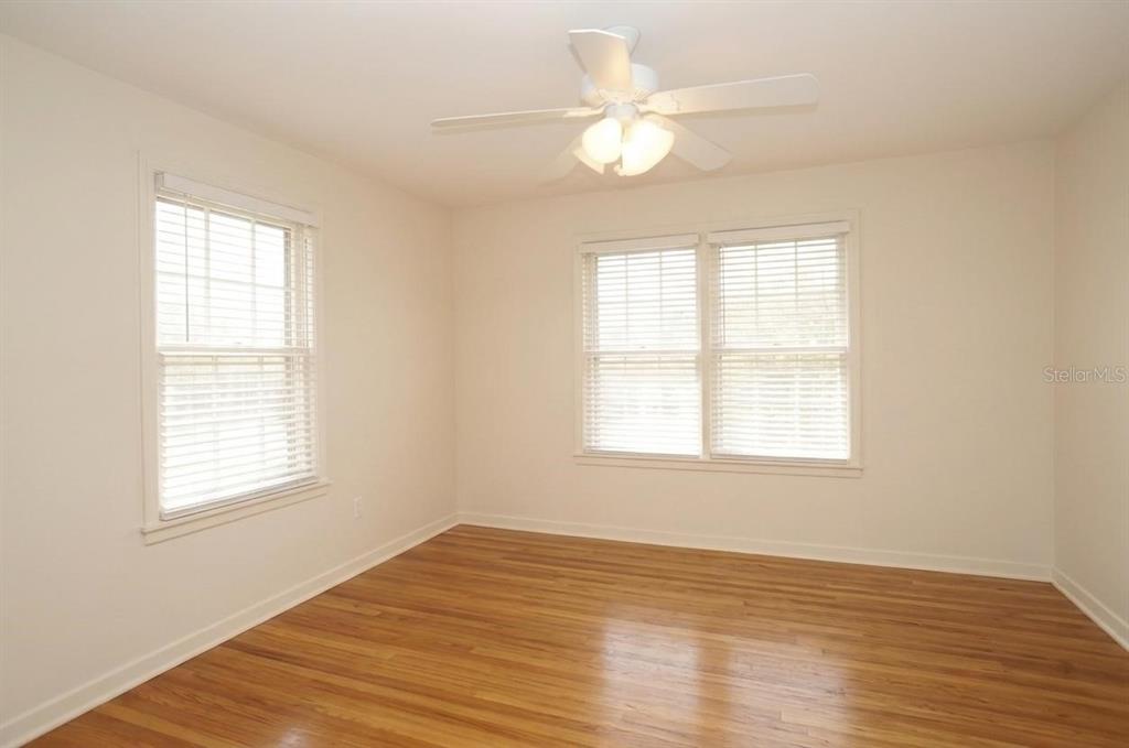 An empty bedroom features light-colored walls, wood flooring, a ceiling fan, and two windows — 305 S AUDUBON AVENUE, TAMPA, FL