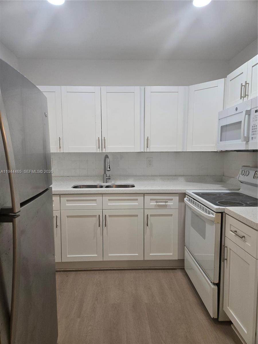 A kitchen features white cabinets, stainless steel appliances, and light-colored countertops — 190 SE 12th Ave # 1B, Pompano Beach FL 33060, POMPANO BEACH, FL