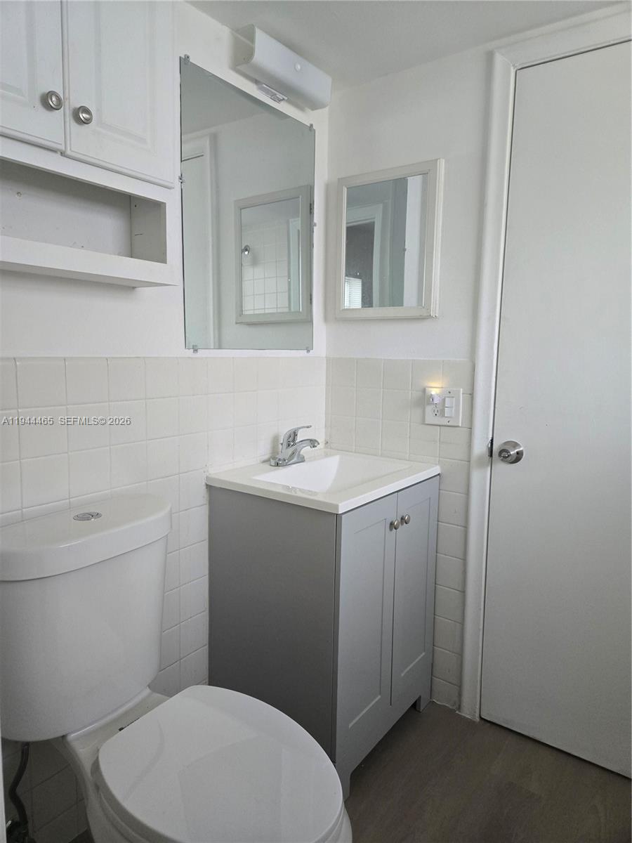 A small bathroom features a white toilet, a gray vanity, and a wall-mounted mirror — 190 SE 12th Ave # 1B, Pompano Beach FL 33060, POMPANO BEACH, FL