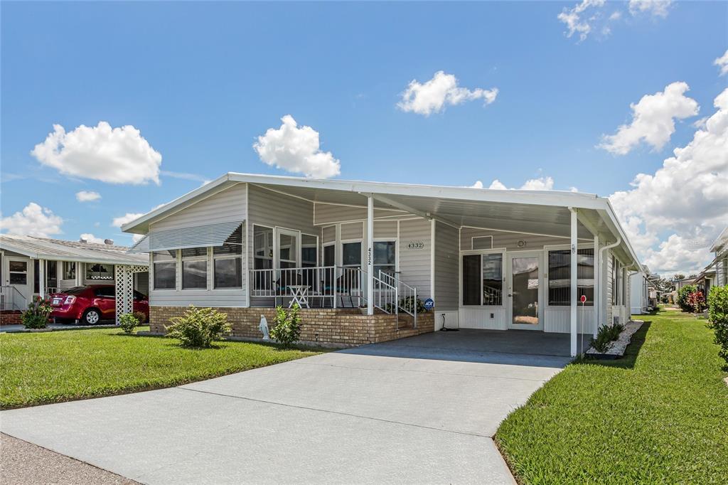 A single-story manufactured home features light gray siding, a brick base, and a covered carport — 4332 CHERRYWOOD STREET, WINTER HAVEN, FL